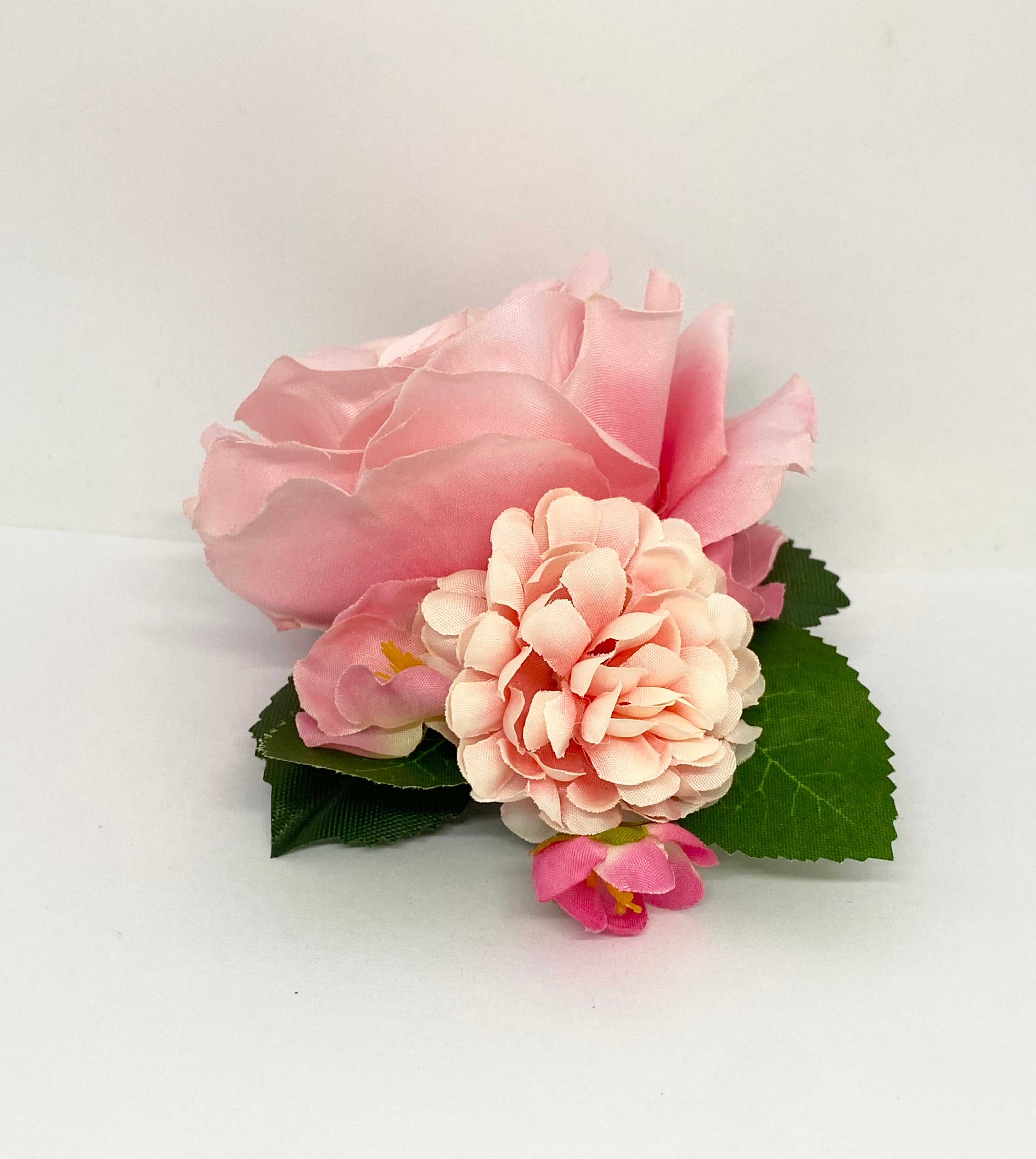 American Beauty A pink rose hair flower with a small green leaf attached, positioned against a white background. Pinup hair styling.