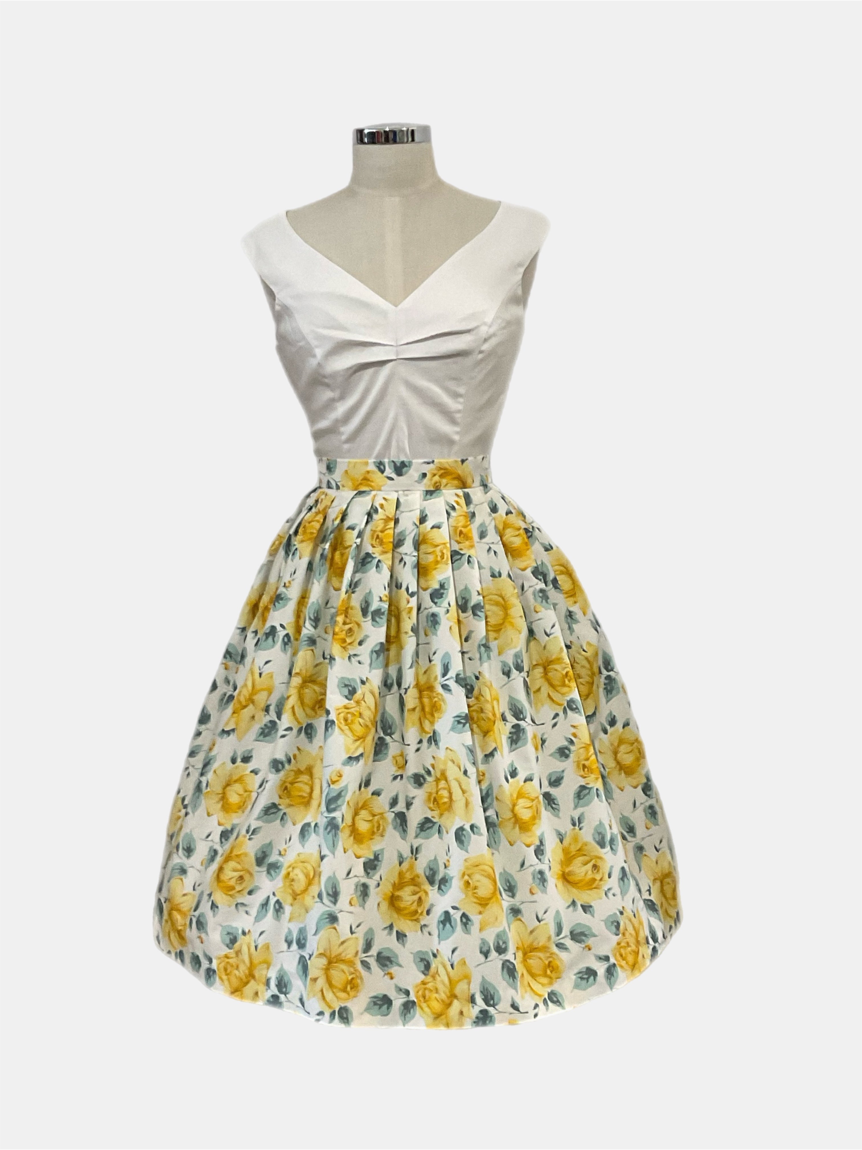 Corina buttercup yellow rose Floral 1950s vintage style skirt with pleats around the waist and a floral pattern in yellow and green on a white background.
