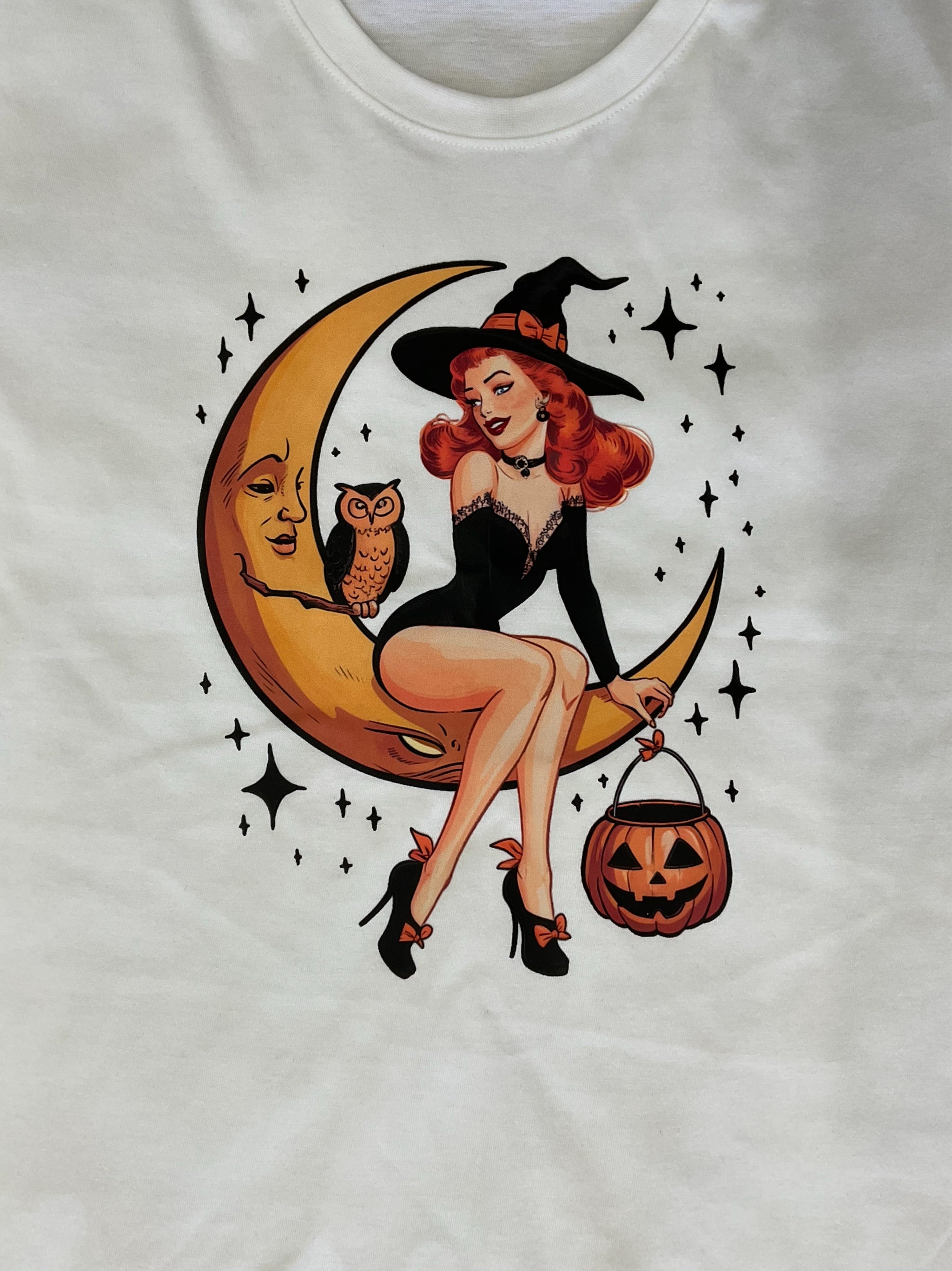 Halloween pin-up , vintage style T-shirt with a graphic print of a woman with a witch's hat, a crescent moon, and a pumpkin. 