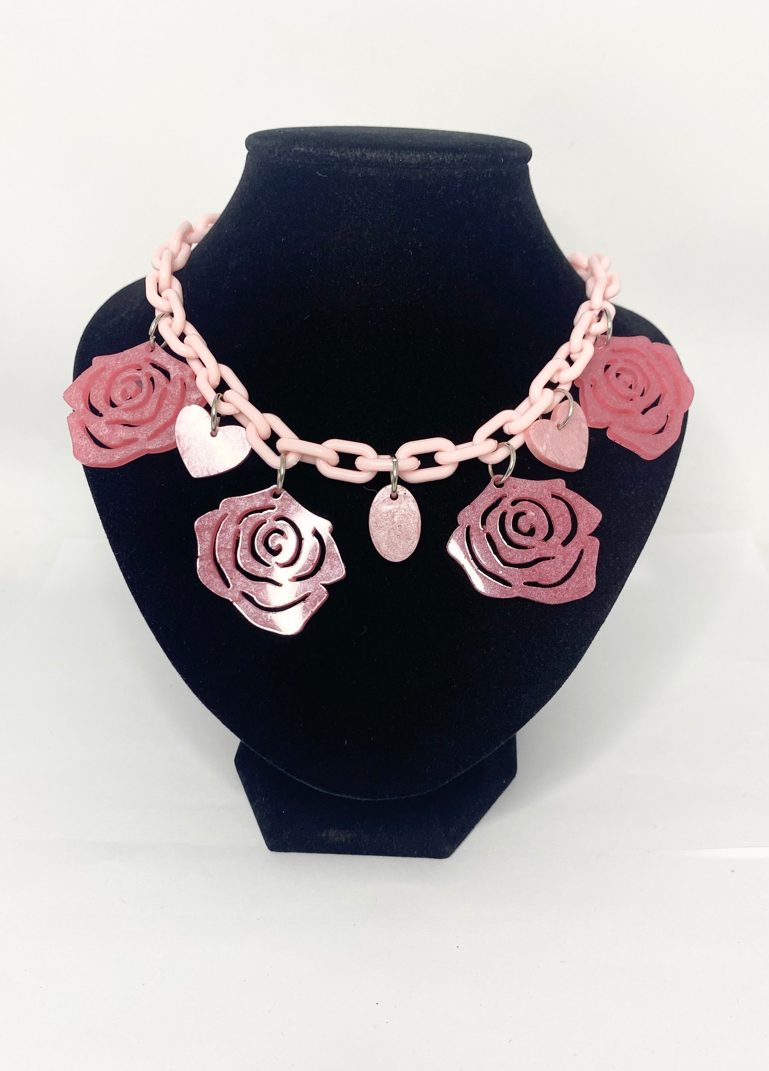 Hearts And Roses 1950s style fun Pink necklace with rose-shaped charms on a white backgro