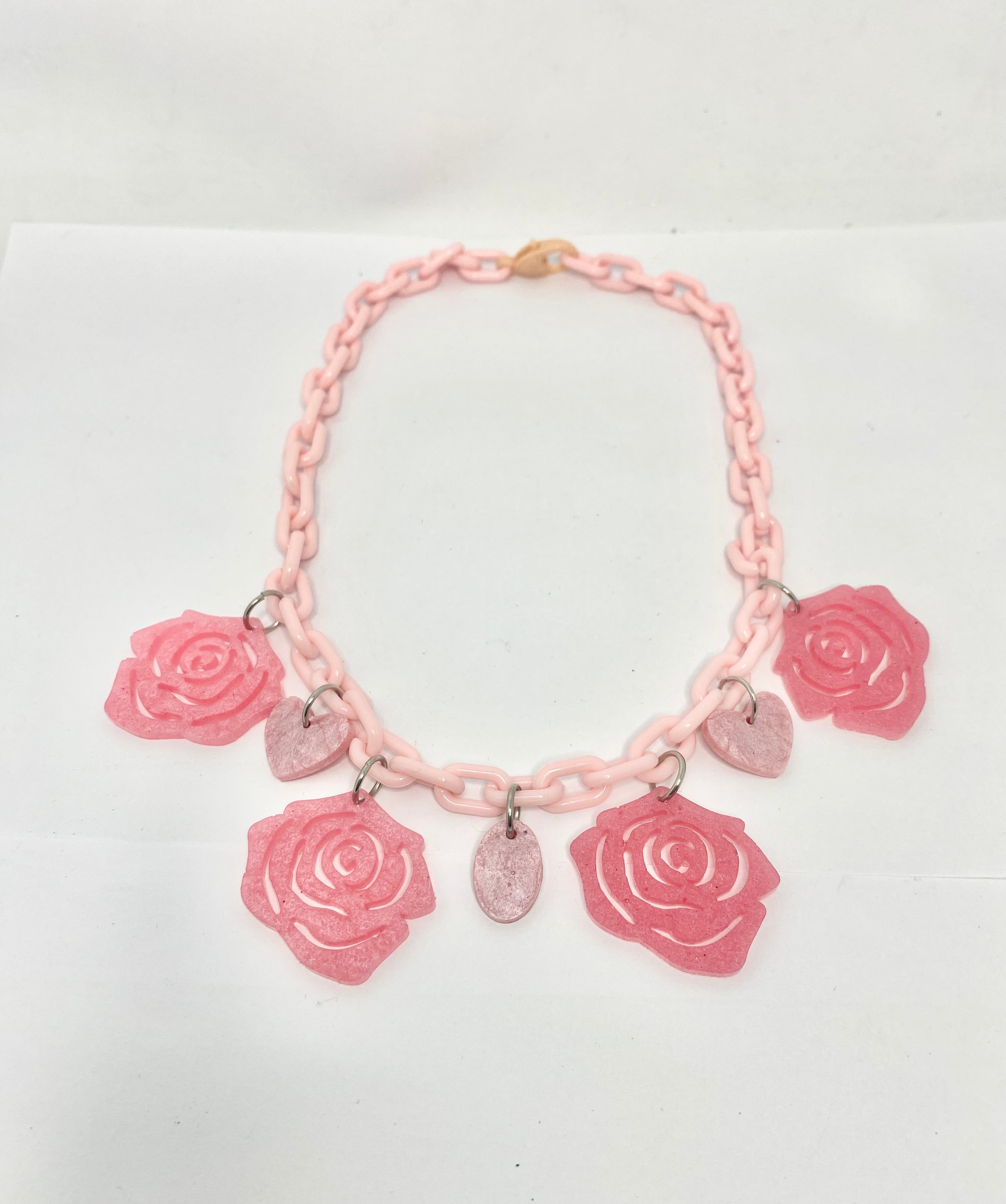 Hearts And Roses 1950s style fun Pink necklace with rose-shaped charms on a white background