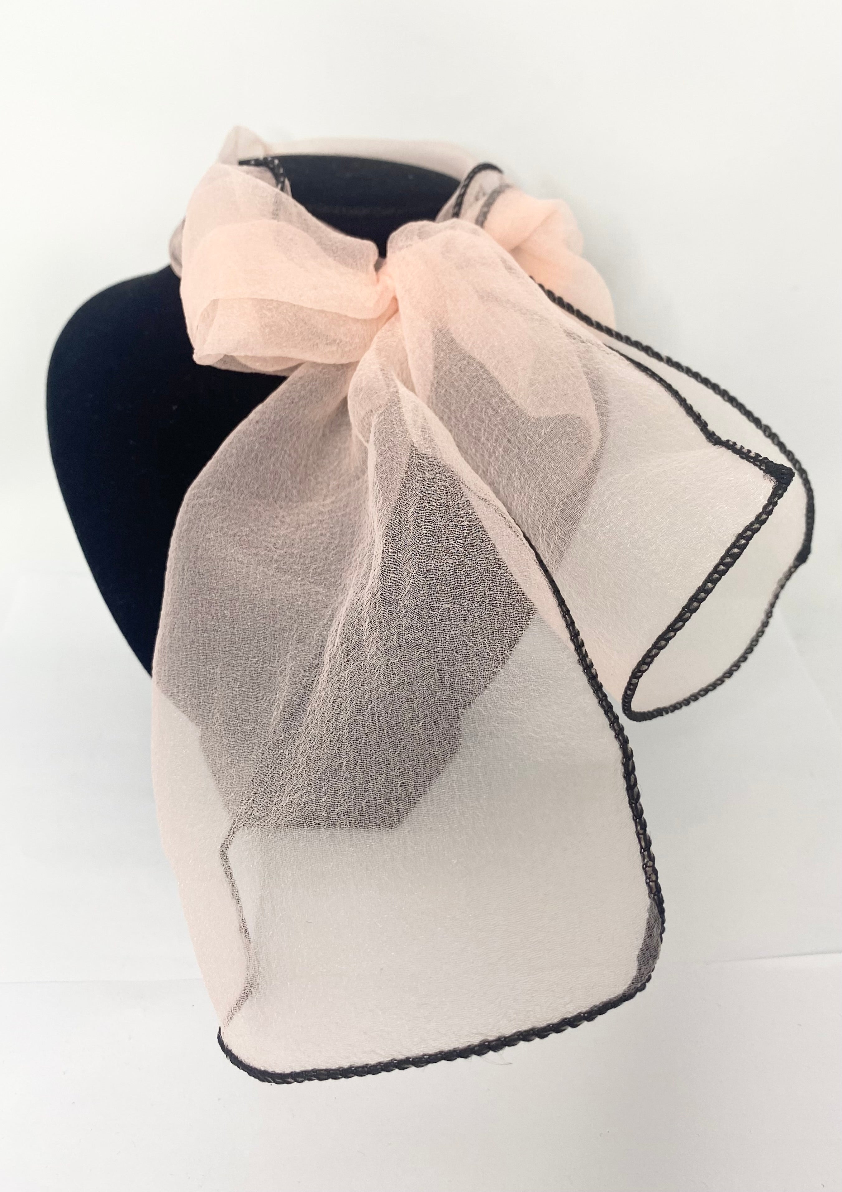 Organza peach vintage style Sheer beige scarf with black trim on a mannequin head against a white background