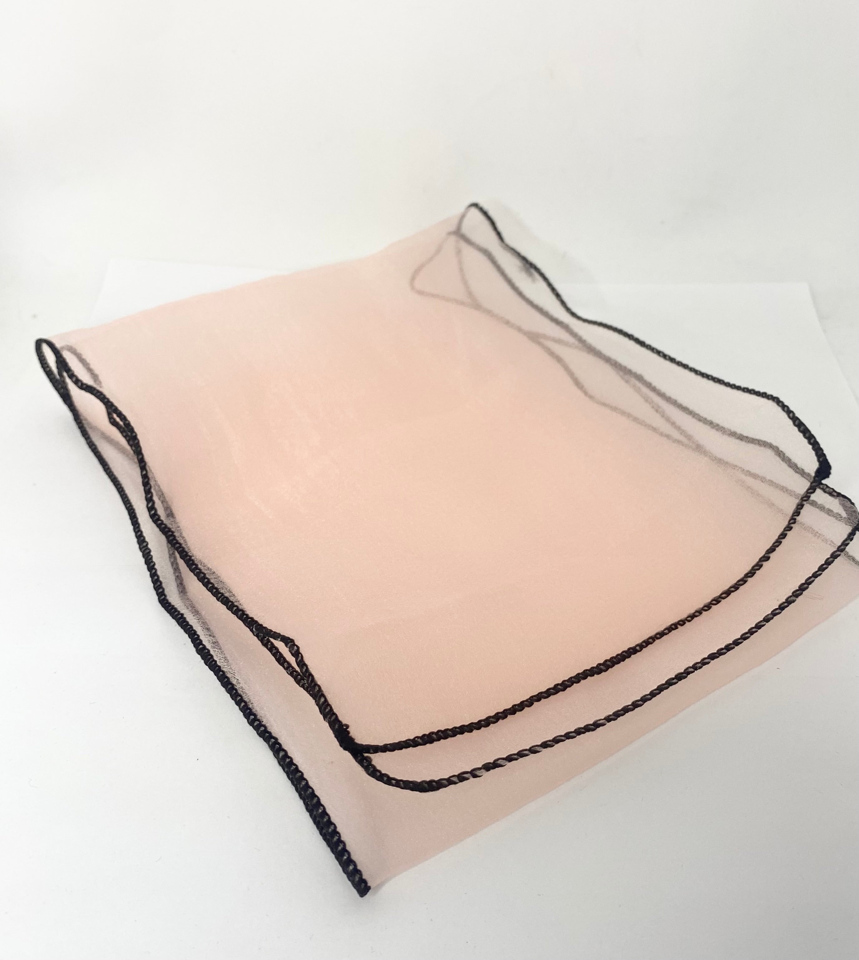 Sheer beige pillowcase with black lace trim on a white background