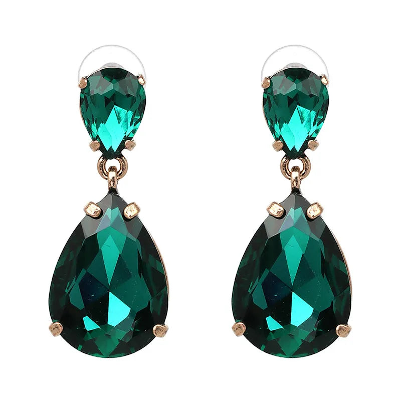 Green teardrop vintage style earrings with gold accents on a beige background. Old Hollywood glamour