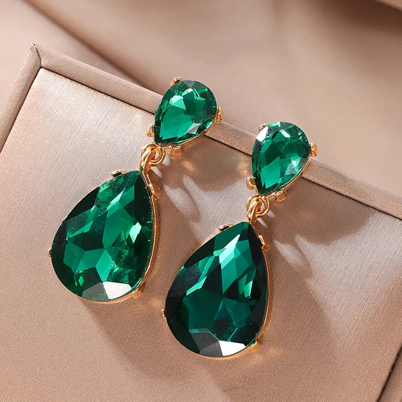 Green teardrop vintage style earrings with gold accents on a beige background. Old Hollywood gamour