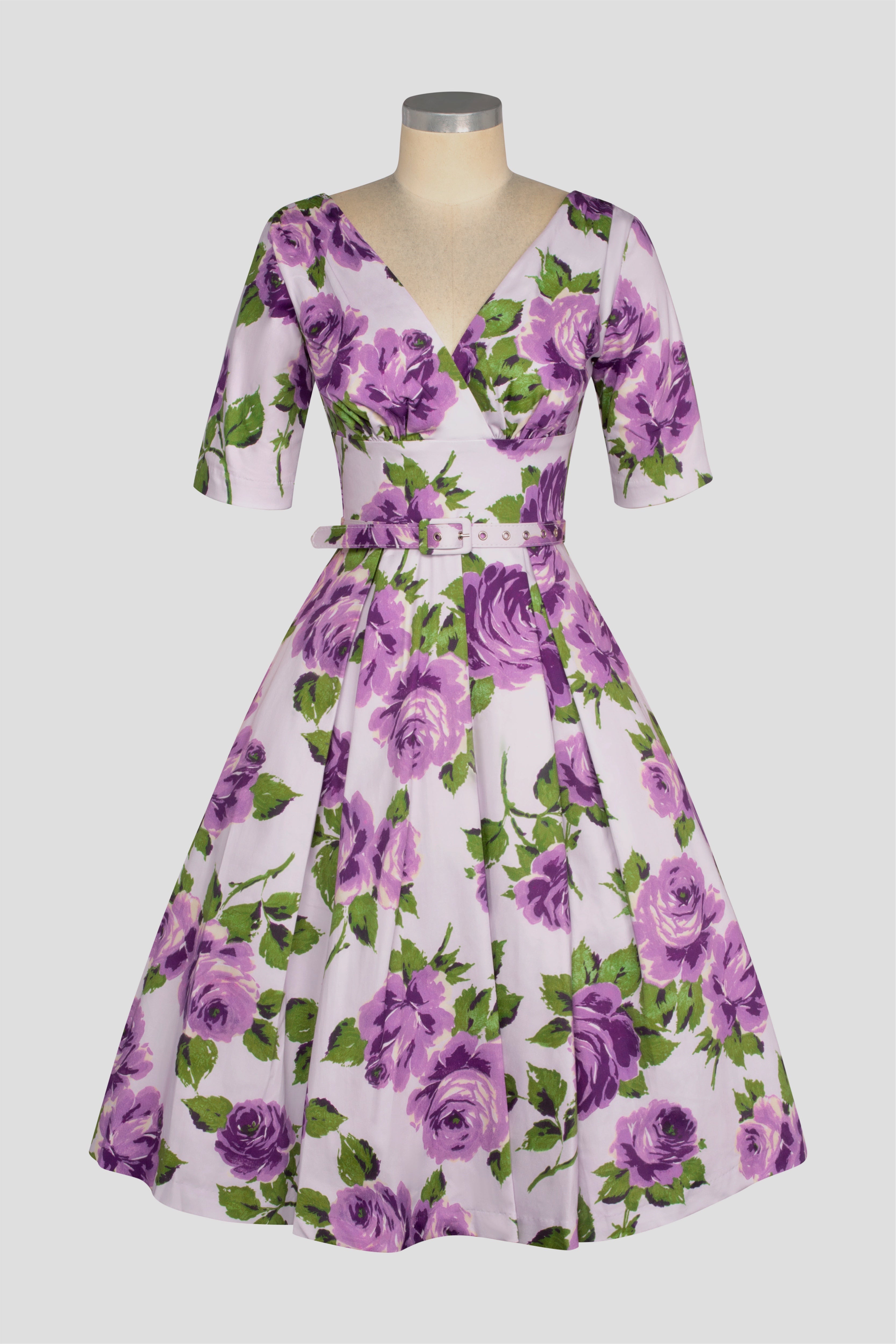 Valentina toscana A vintage style sleeve dress with a V-neck neckline and purple floral pattern. The dress features a belt and finishes with a full skirt.